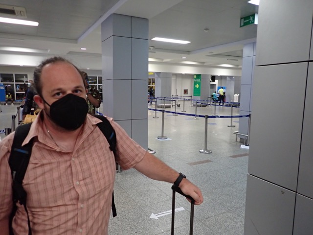 man in mask standing in line at an airport