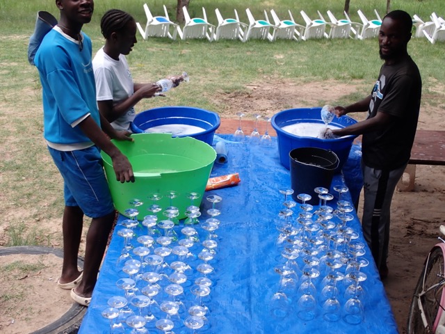 three people washing glassware for a party