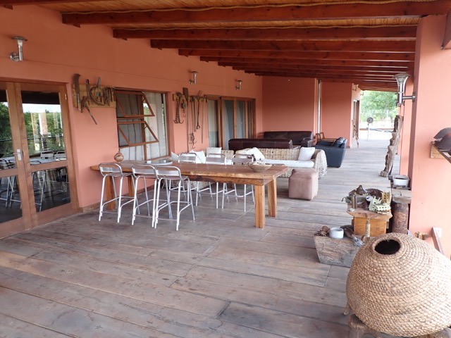 back patio of a safari lodge with table, chairs, couches, and artefacts