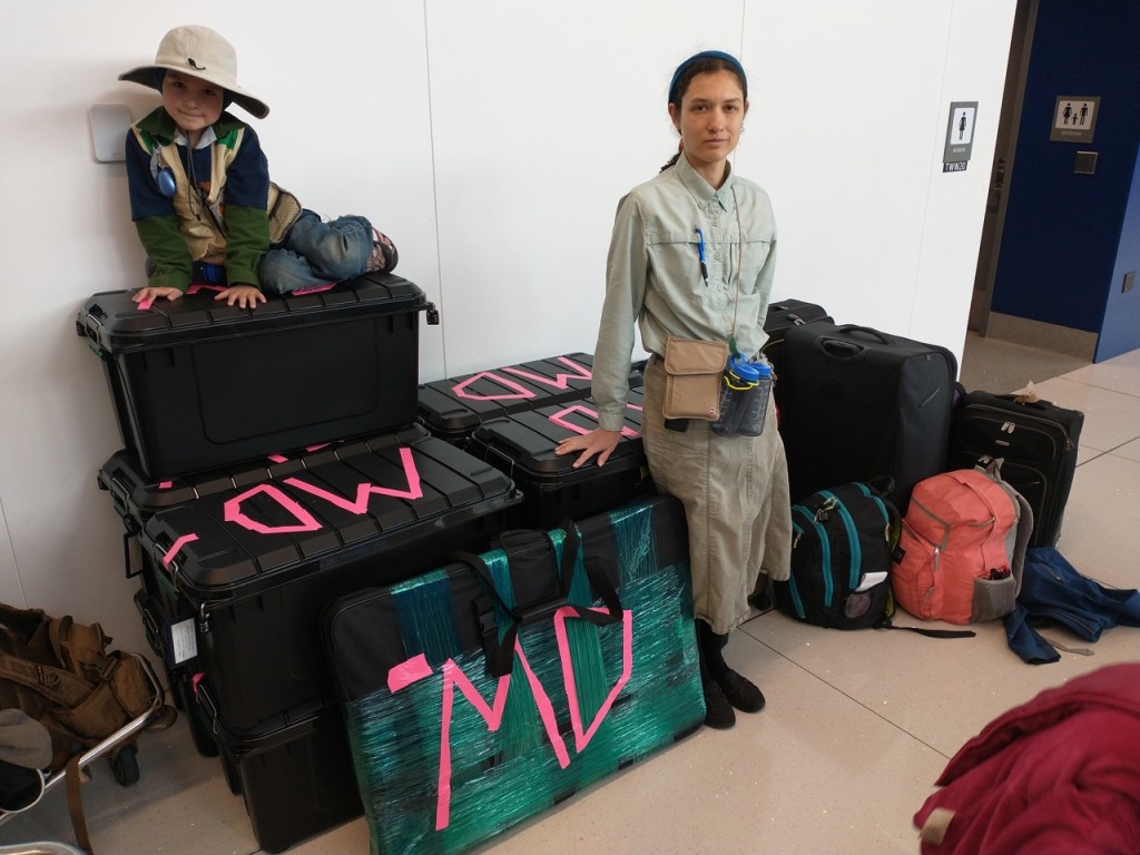 a woman and child with a pile of baggage at an airport before checking in