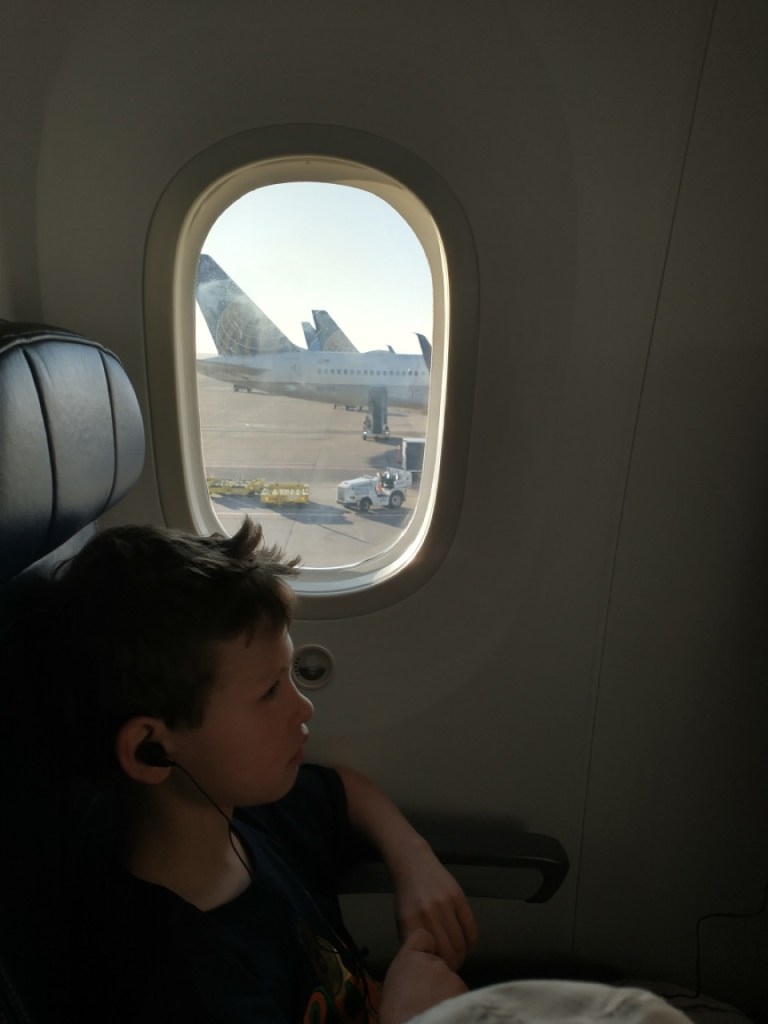 a boy sits next to an airplane window before takeoff