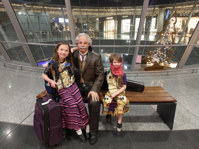 two girls sit with Einstein statue on Frankfurt airport bench