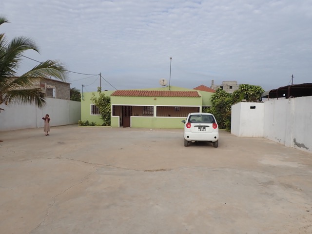 concrete front yard of walled compound looking toward the house with car