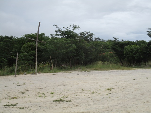 wooden cross at one end of a dirt field